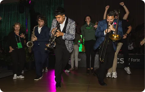 Attendees dancing with live saxophone and trombone at Be Herd 2026