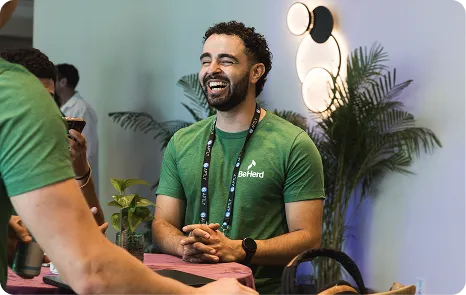 Attendee in a Be Herd shirt at a sponsor table during Be Herd 2026