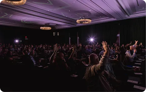 Attendees raising hands in the main hall at Be Herd 2026